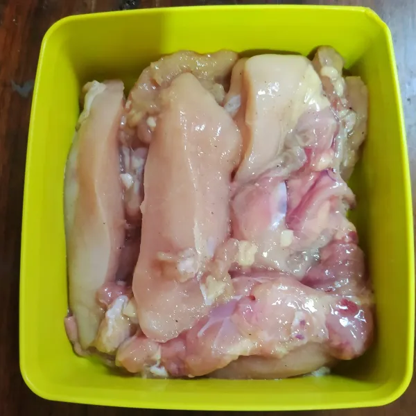 Ayam fillet diiris memajang. Marinasi dengan bawang putih, lada dan garam selama 2 jam.