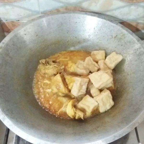 Masukan tahu apung. Tutup lagi wajannya sebentar (ungkep) agar bumbu meresap ke dalam tahu.