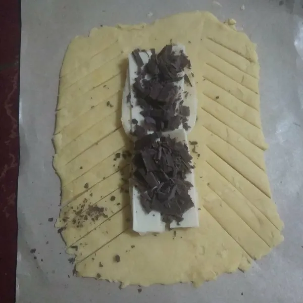 Beri pisang dibagian tengah, tambahkan irisan keju slice dan coklat batang. kerat-kerat sisinya.