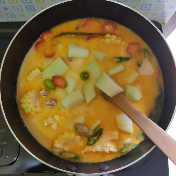 Masukkan labu siam, kacang bogor, jagung manis, dan biji melinjo. Masak hingga matang lalu beri garam, gula pasir dan kaldu jamur. Koreksi rasanya.