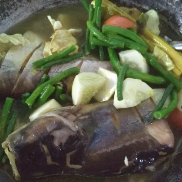 Tambahkan kacang panjang, tomat, dan timun. Masak hingga ikan patin matang sambil dibalik dengan hati-hati karena ikan mudah hancur, tambahkan gula, garam, dan penyedap. Koreksi rasa.