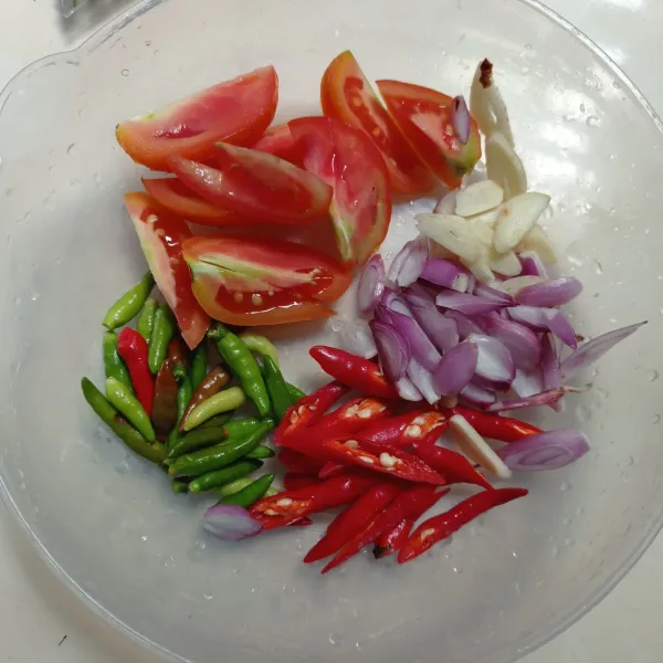 Potong tomat, iris bawang merah, bawang putih dan cabe merah keriting, biarkan utuh cabe rawit ijo, sisihkan