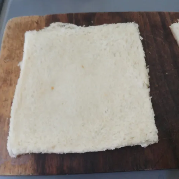 Buang bagian pinggir roti tawar, kemudian gilas hingga tipis.