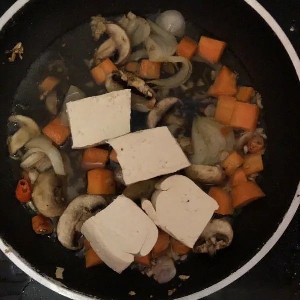 Masukkan wortel, jamur champion, tahu, bumbu, dan air. Masak hingga wortel matang.