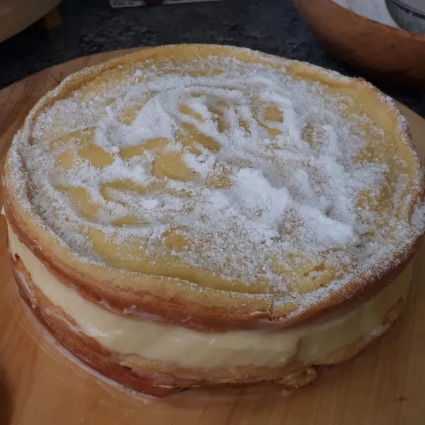 Keluarkan kue dari kulkas. Keluarkan kue dari loyang, taburi atasnya dengan gula halus. Sajikan.