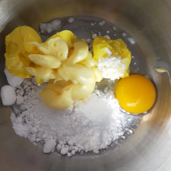 Campur margarin, butter, vanilli bubuk, kuning telur dan gula halus dalam wadah.