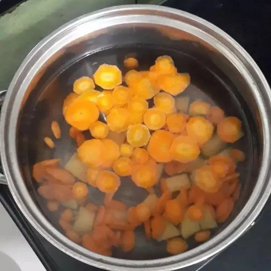 Didihkan air dalam panci, rebus terlebih dahulu wortel dan kentang hingga setengah empuk