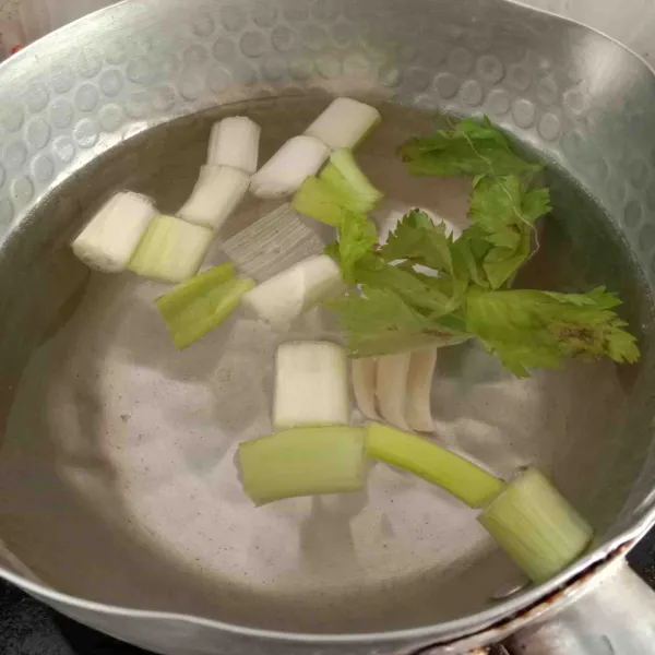 Rebus air, masukkan daun bawang, bawang putih geprek dan seledri, rebus hingga mendidih