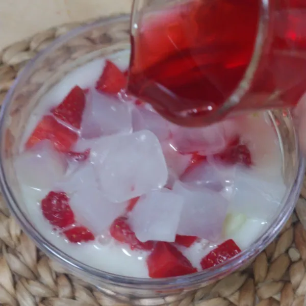 Tambahkan kuah susu yang sudah dingin dan sirup merah, aduk rata