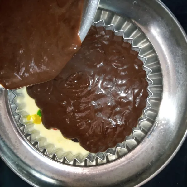 Tuang adonan cokelat di atas adonan putih.