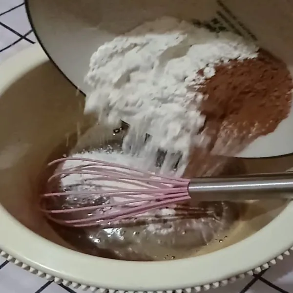 Setelah gula larut sempurna, masukan tepung dan coklat bubuk. Aduk rata. Adonan akan makin kental dan berat. Gakpapa lanjutkan mengaduk hingga tercampur rata sempurna.