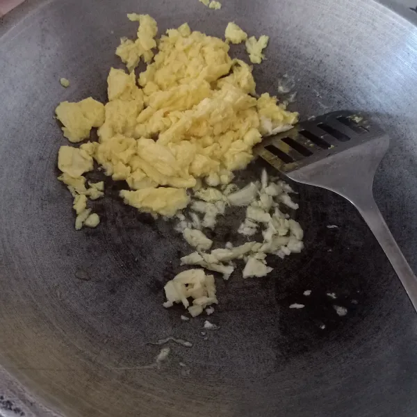 Goreng telur orak arik dengan sedikit minyak goreng sampai matang, sisihkan, lalu tumis bawang putih cincang sampai harum