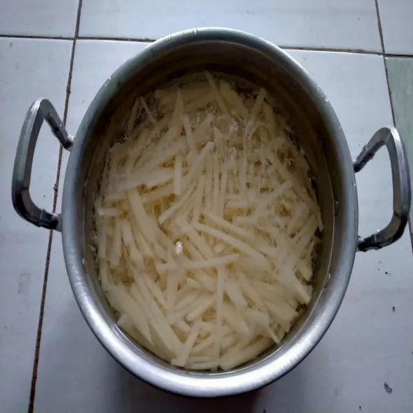 Potong-potong kentang berbentuk korek api, kemudian rendam ke dalam air. Diamkan selama 15 menit.