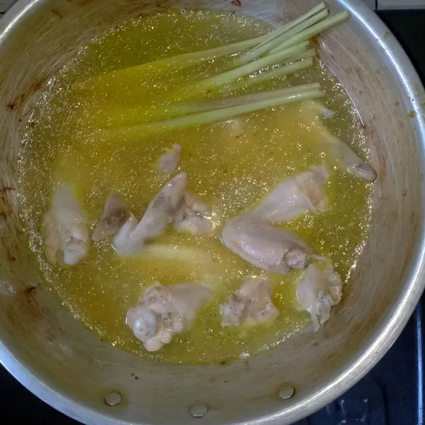 Masukkan air rebusan ayam ke dalam wajan tumisan bumbu, sambil disaring. Lalu masukkan serai dan ayam.