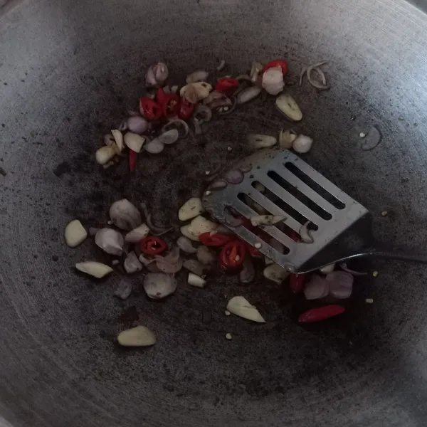 Masukkan bumbu iris, kunyit bubuk dan terasi ke dalam wajan dengan sedikit minyak bekas goreng terong. Remas-remas dan aduk rata, kompor dalam keadaan mati.