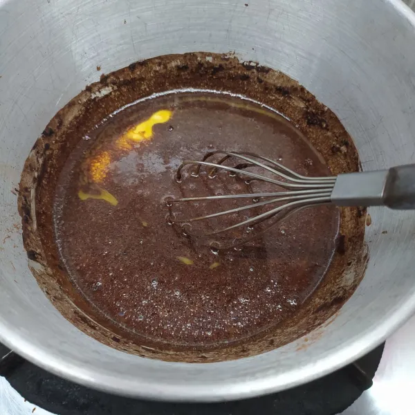 Dalam panci campur air, coklat bubuk, butter dan minyak goreng. Masak di atas api sedang sampai semua bahan larut. Angkat dan sisihkan.