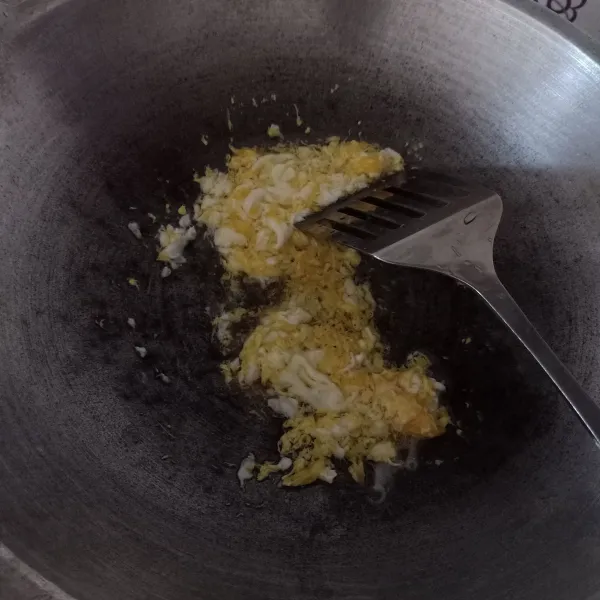 Goreng telur orak-arik dengan sedikit minyak goreng, lalu pinggirkan di tepi wajan.