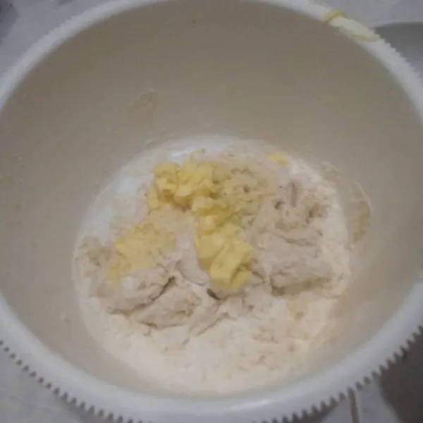 Tuang air ragi, aduk rata lalu tambahkan garam dan margarin. Aduk dengan tangan hingga tercampur rata.