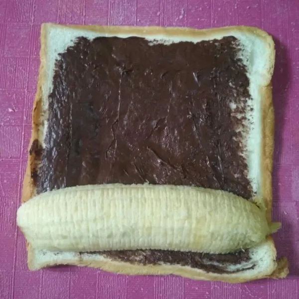 Oles dengan selai coklat dan beri pisang raja gulung perlahan sambil di padatkan.