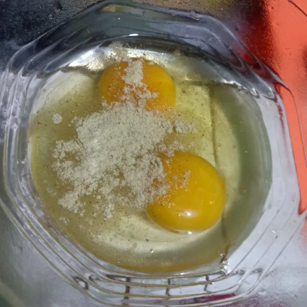 Pecahkan telur ke dalam mangkok lalu beri bubuk kaldu jamur.