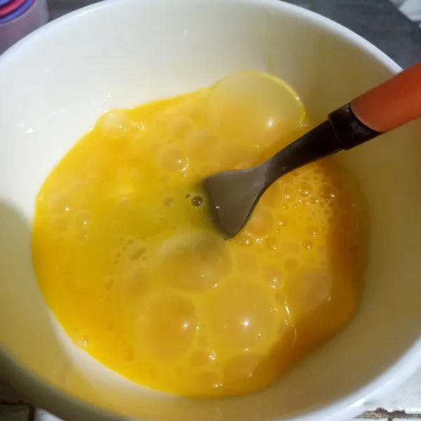 Pecahkan telur ke wadah mangkuk, lalu kocok telur.
