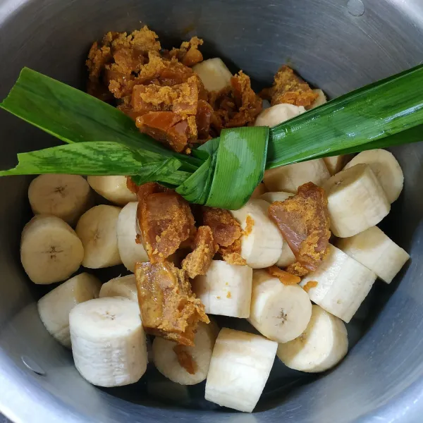 Selanjutnya masukkan pisang, gula merah dan daun pandan. Tutup pancinya, rebus sebentar.