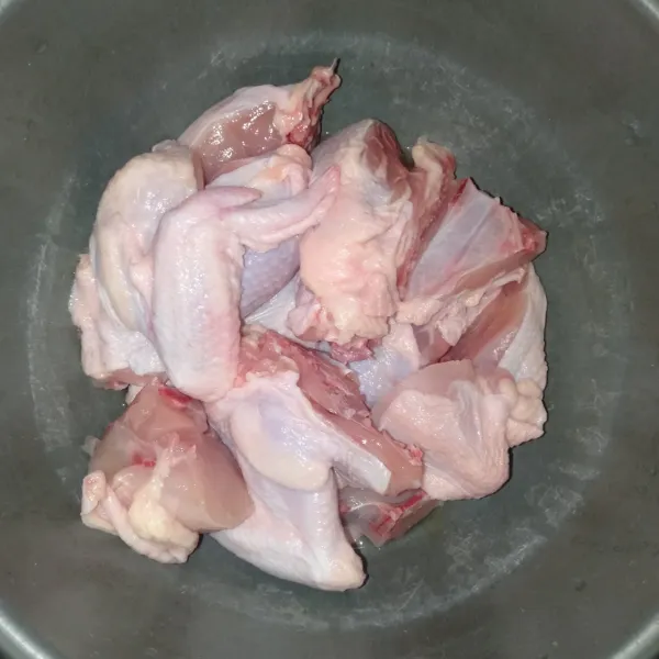 Potong 1 kg ayam menjadi 12 bagian, lalu cuci bersih.