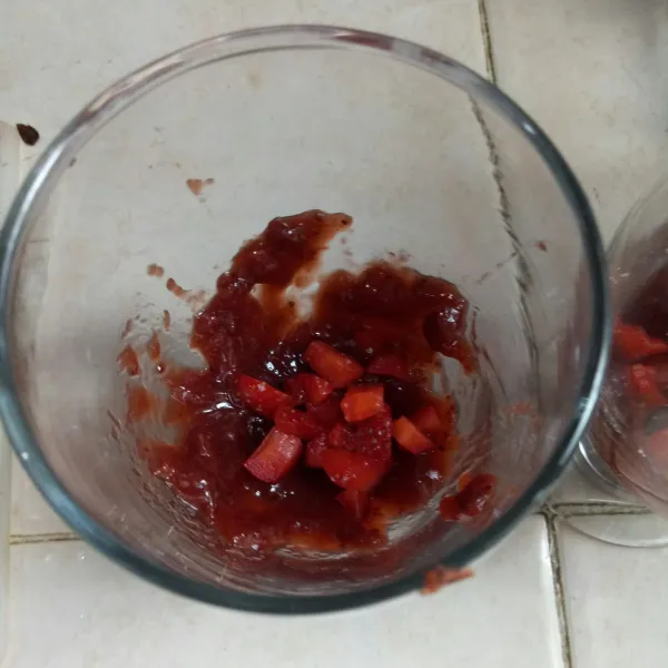 Beri selai di dasar gelas dan beri irisan strawberry
