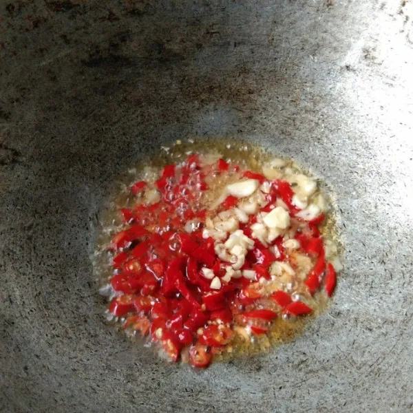 Panaskan wajan dengan minyak secukupnya, goreng irisan cabe merah keriting dan bawang putih hingga harum