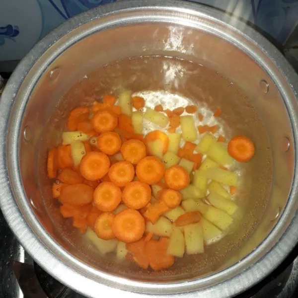 Rebus air hingga mendidih lalu masukkan kentang dan wortel.