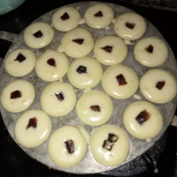 Panaskan cetakan dan oles tipis dengan minyak goreng. Tuang adonan secukupnya dan beri topping kismis/kurma, masak hingga matang dan siap disajikan.