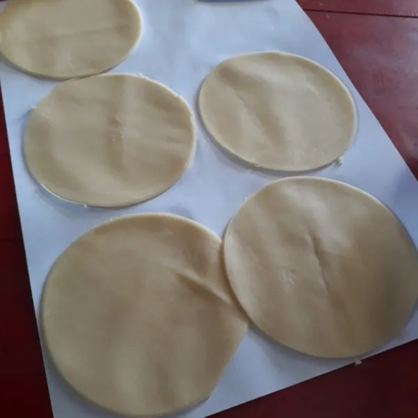 Giling kulit pastel dengan penggiling pasta dengan ketebalan disesuaikan lalu buat lingkaran dengan piring kecil.