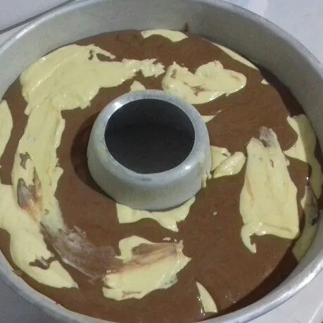 Masukkan adonan ori dan coklat bergantian ke dalam loyang yang sudah dioles margarin dan ditaburi tepung. Hentak-hentakkan. Masukkan dalam oven yang sudah dipanaskan.