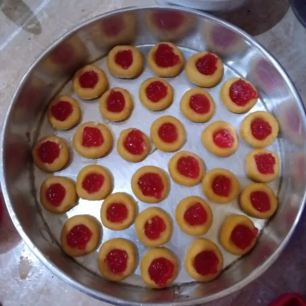Bentuk adonan bulat, tekan bagian tengahnya. Isi dengan selai strawberry