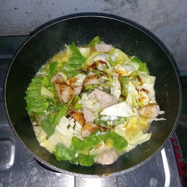 Masukkan pakcoy, kubis, bakso, gula, garam lada bubuk dan kecap manis. Aduk rata. Masak sampai mendidih dan layu.