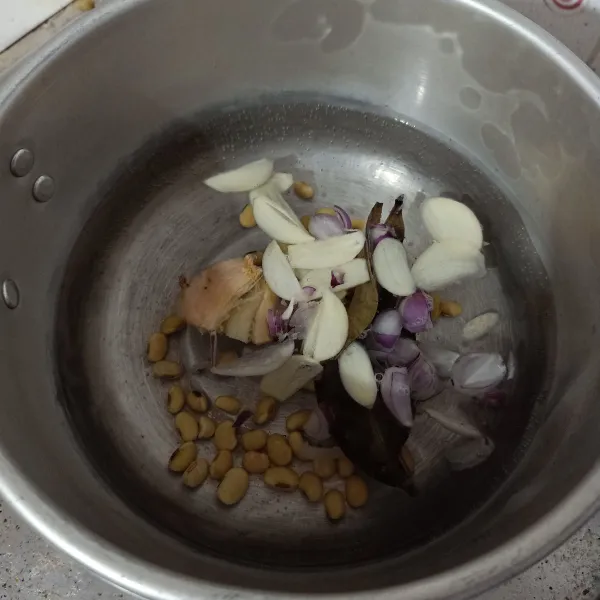 Rebus air, kacang kedelai, bawang merah, bawang putih, lengkuas dan daun salam. Masak sampai mendidih.