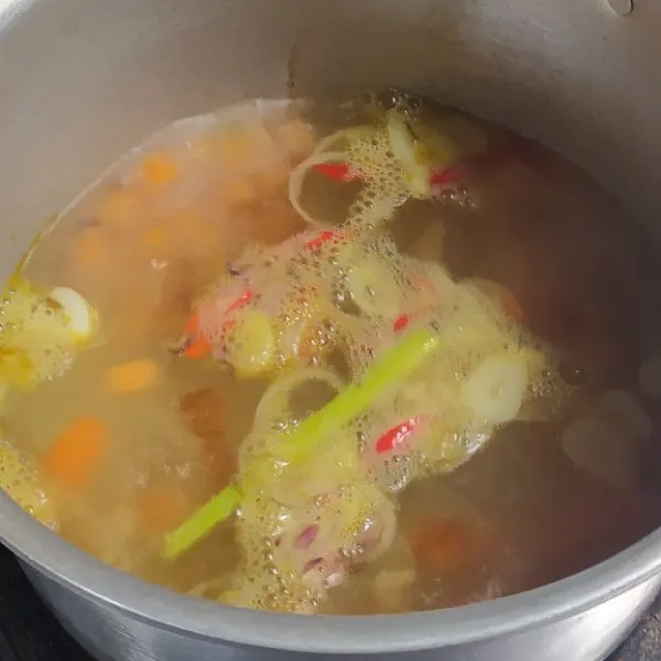 Masukkan bumbu tumis dan wortel ke dalam rebusan air.