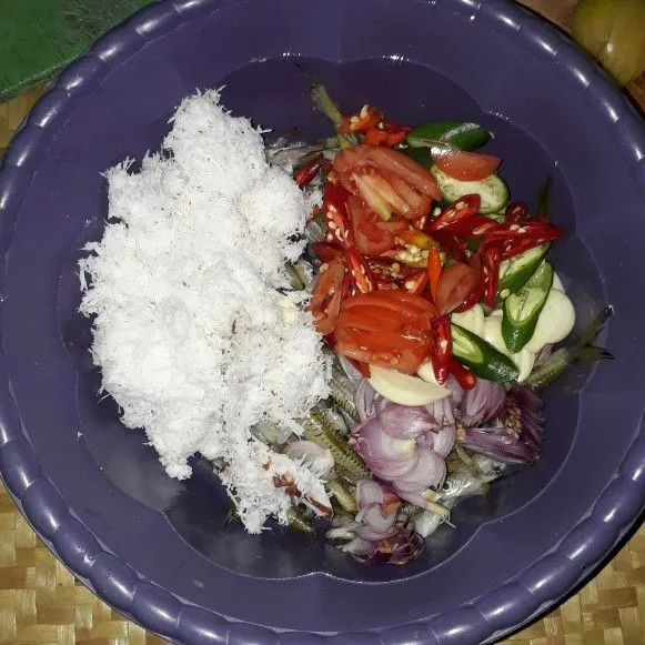 Masukkan kelapa parut, bawang merah, bawang putih, cabe, dan tomat dalam baskom yang berisi ikan, lalu aduk hingga rata.