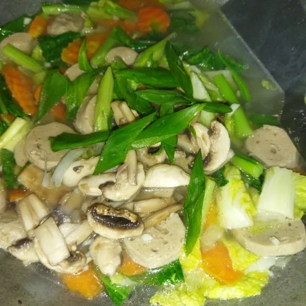 Lalu masukkan daun bawang dan jamur kancing, aduk rata lalu beri garam, kaldu bubuk dan saus tiram, aduk rata dan cicipi.