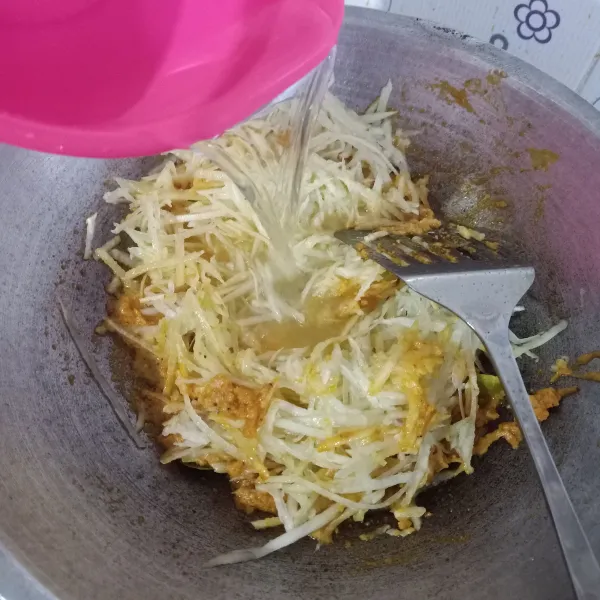 Masukkan pepaya serut, lalu tambahkan air dan aduk rata.