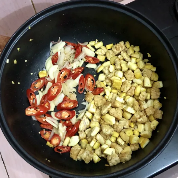 Setelah tahu dan tempe matang kecokelatan, masukkan bawang putih bawang merah dan cabe merah tumis hingga harum, setelah harum, aduk rata
