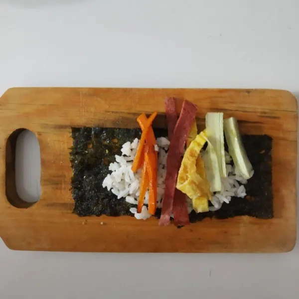 Beri isian telur, tumisan wortel, smoke beef, dan timun kemudian gulung-gulung lakukan sampai selesai