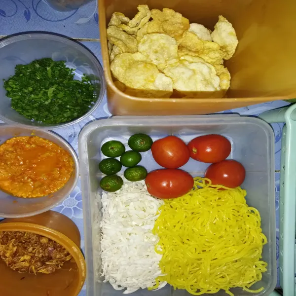 Siapkan bahan pelengkap soto mie, seperti mie kuning basah, kol yang diiris tipis, tomat, jeruk limo, bawang goreng, irisan daun seledri, sambal dan emping goreng.