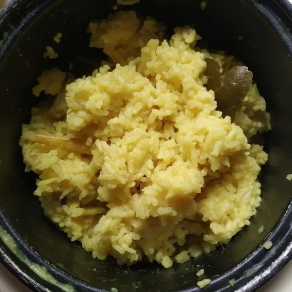 Masak nasi kuning seperti menanak nasi biasa dengan rice cooker, ketika sudah matang, buka rice cooker dan aduk-aduk nasi kuning agar tanak