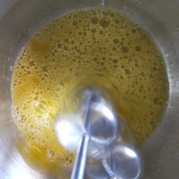 Masukkan gula pasir ke dalam air, panaskan hingga larut sambil diaduk. Diamkan dulu hingga hangat. Masukkan telur dan baking soda ke dalam wadah. Mixer hingga mengembang.