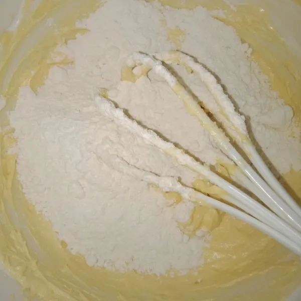 Lalu masukkan vanila dan susu bubuk, tambahkan tepung sedikit demi sedikit hingga tercampur rata