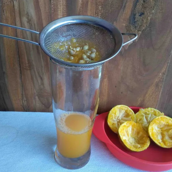 Peras dan saring buah jeruk. Masukkan sari buah jeruk ke dalam gelas.