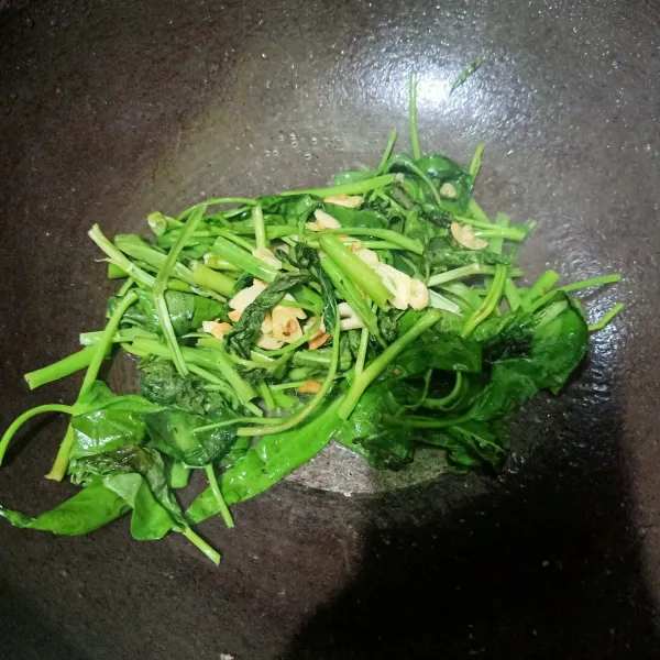 Wajan yang berisi osengan bawang putih, setelah harum lalu masukkan daun kangkung.
