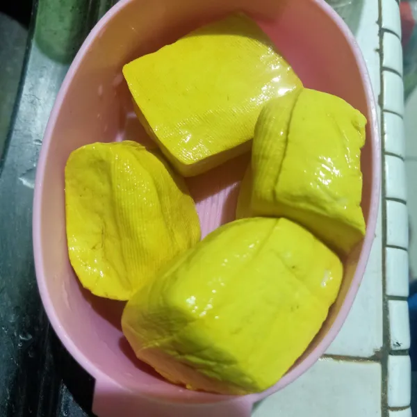 Siapkan tahu lalu bilas dengan air panas. Lalu tiriskan.