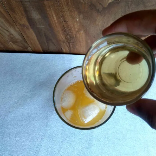 Tambahkan es batu dan simple sirup ke dalam gelas.